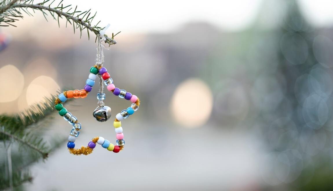 A handmade, beaded star hanging from a branch.