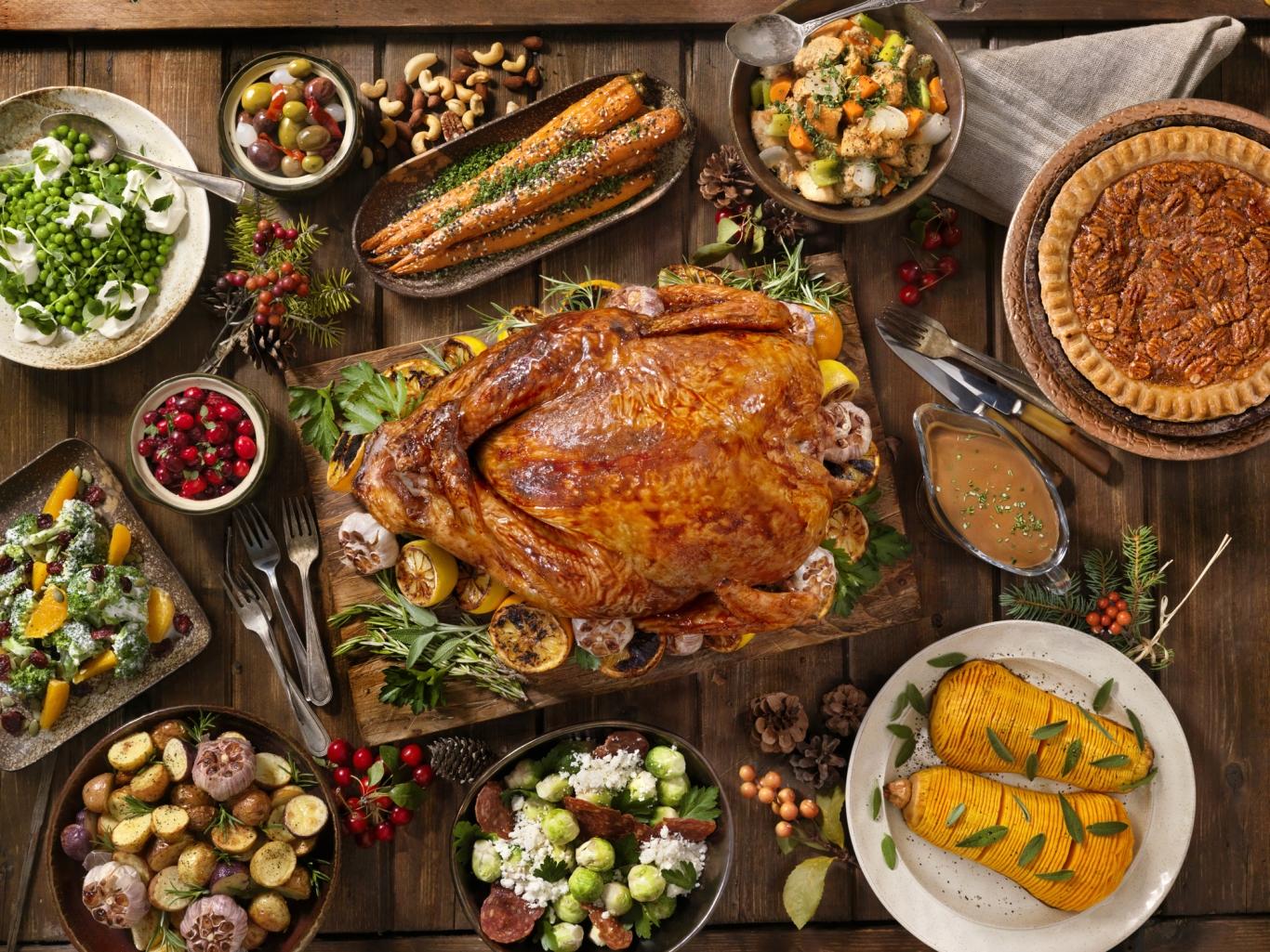 A variety of Thanksgiving dishes around a cooked turkey.