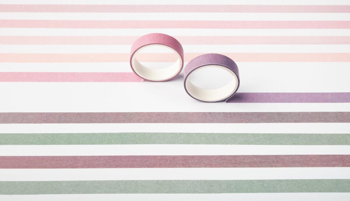 Various colors of Washi tape create stripes on a white wall.