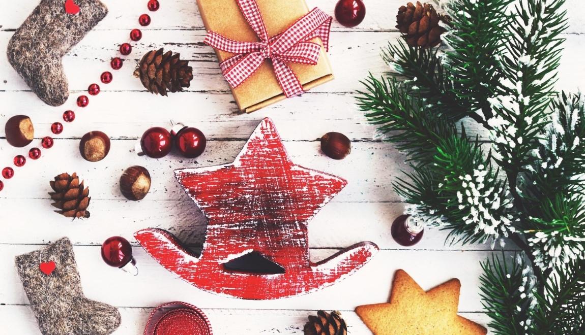 Wooden ornaments on a table surrounded by cranberries and tree branches.