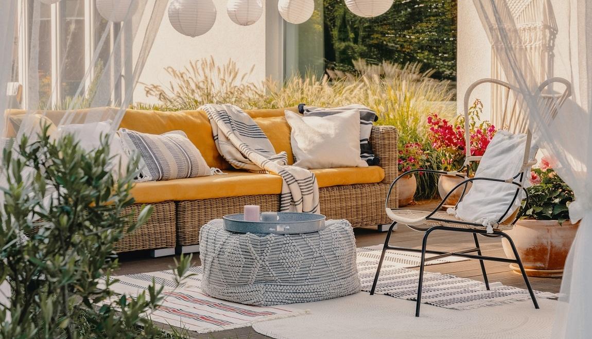 A yellow couch with throw pillows on the balcony.