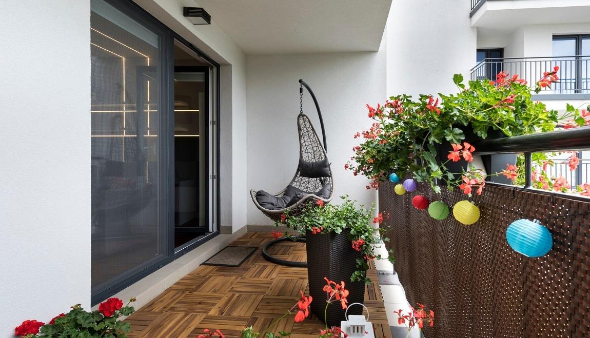 A small apartment balcony with planters and an egg chair. 