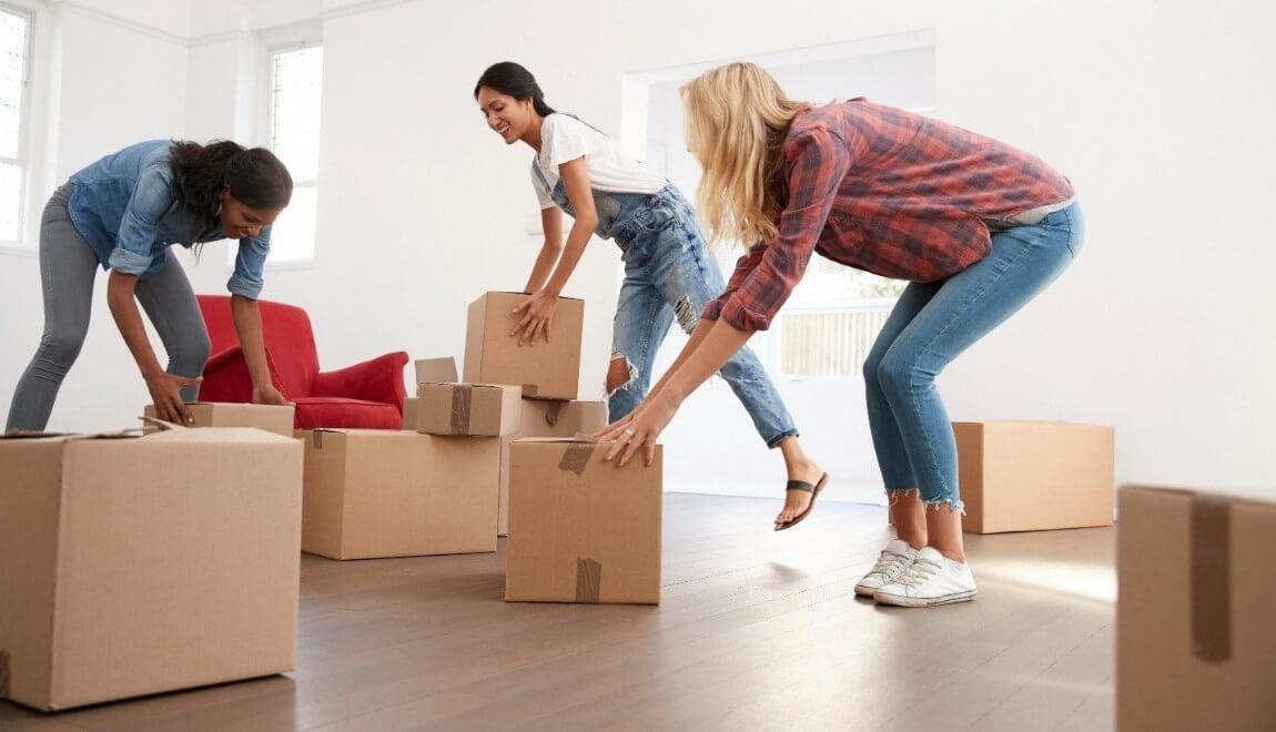 Women moving boxes through a living room