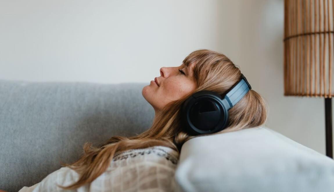 a woman reclines with black headphones covering her ears