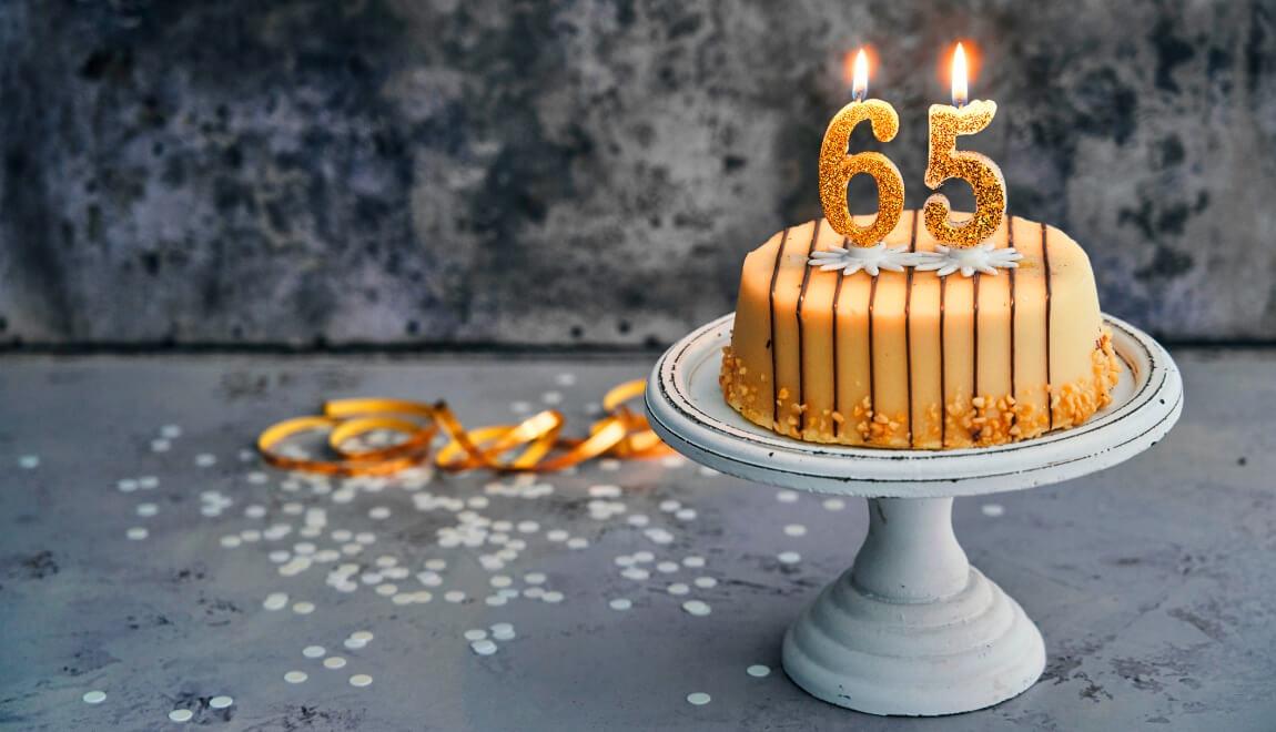 A gold cake with candles in the shape of numbers celebrating 65. 