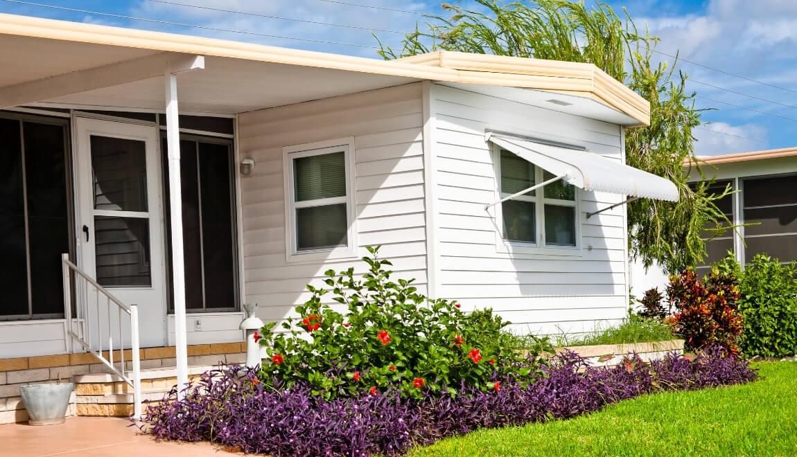 A small flower garden outside of a manufactured home.