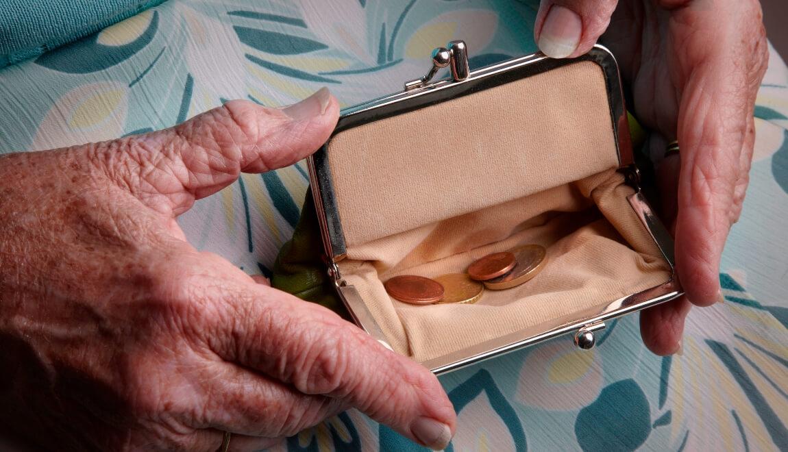 An older person holds an open coin purse.