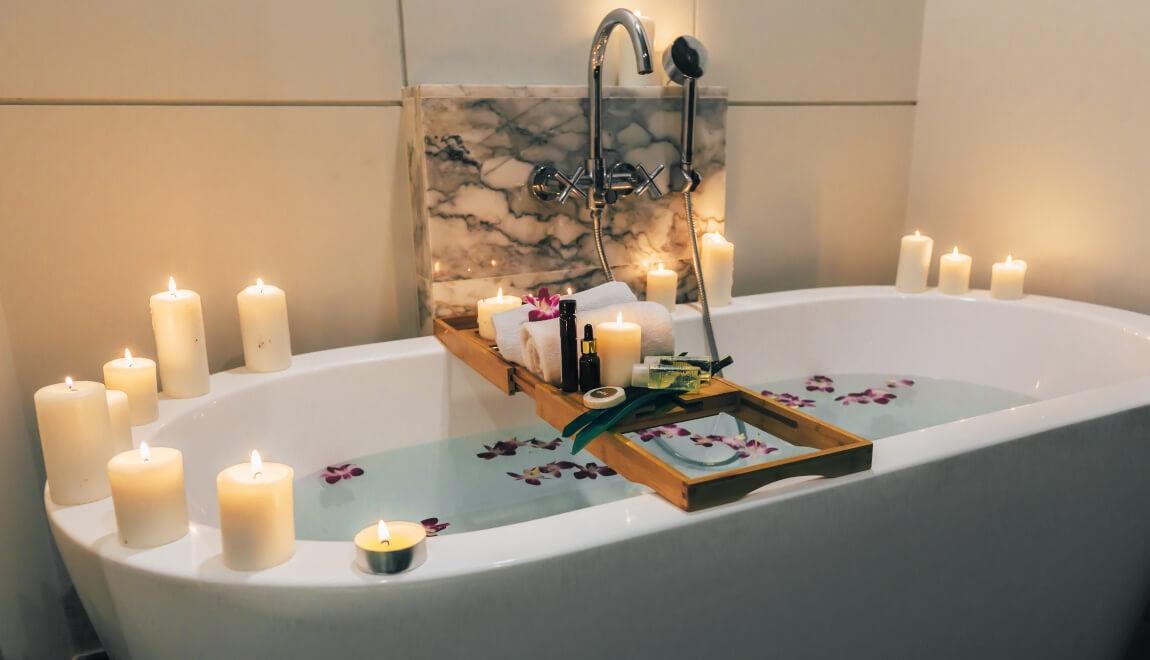 A bath tray holding candles, soaps, and bottles.