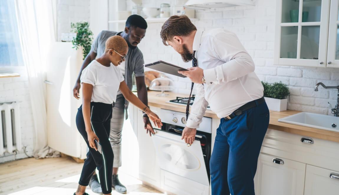 A couple looks over the kitchen during an apartment tour.