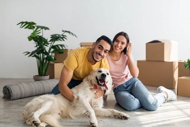 A couple sitting on the floor of their new apartment with their dog. 