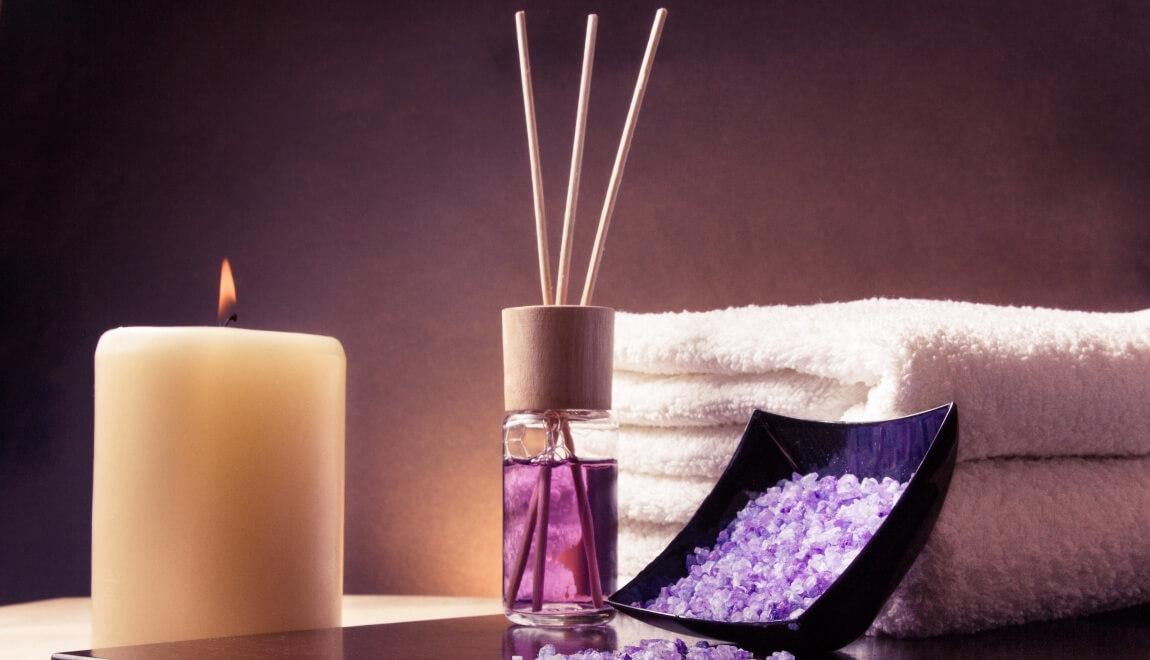 A diffuser and candle next to towels.