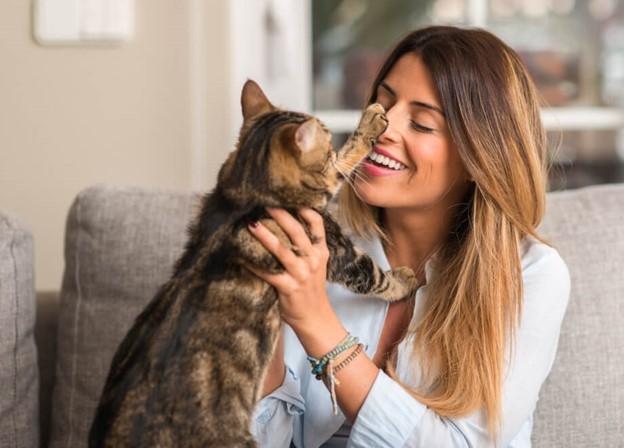 A woman holding a cat and smiling.