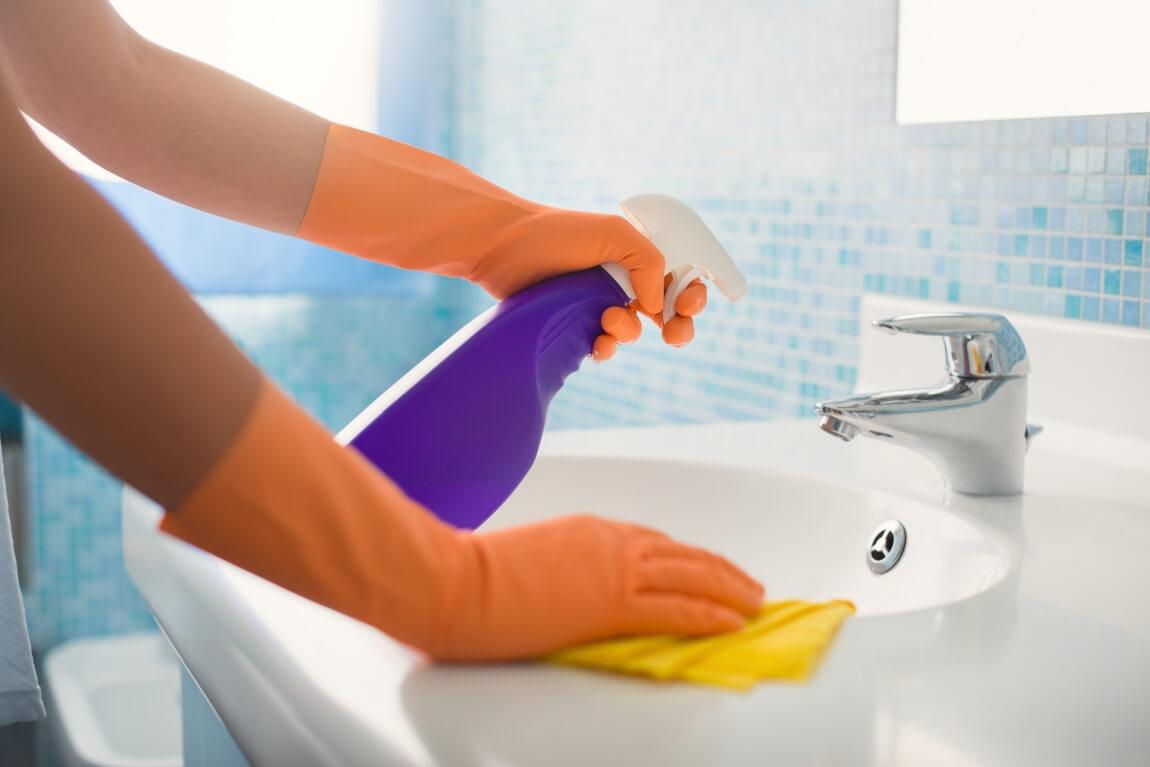 An image of a person wiping a bathroom sink.   