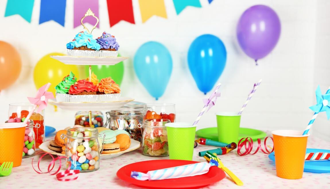 An image of a table with food on it, surrounded with party decor. 