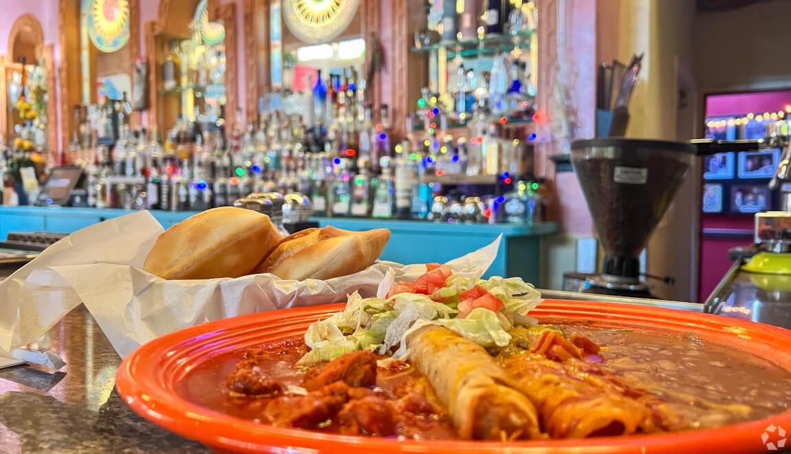 A plate of taquitos and mole sits on the counter of a local restaurant