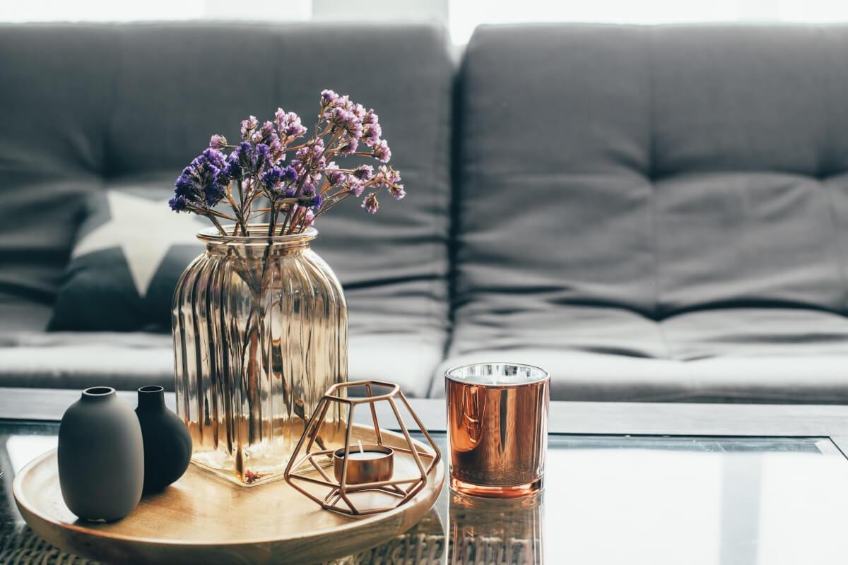 A coffee table is decorated with candles, dried flowers, and decorative vases.