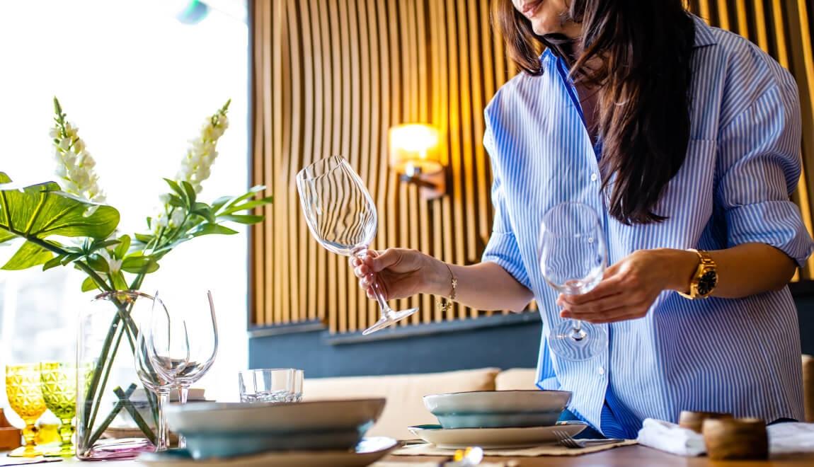 Host arranges glassware for a dinner party.