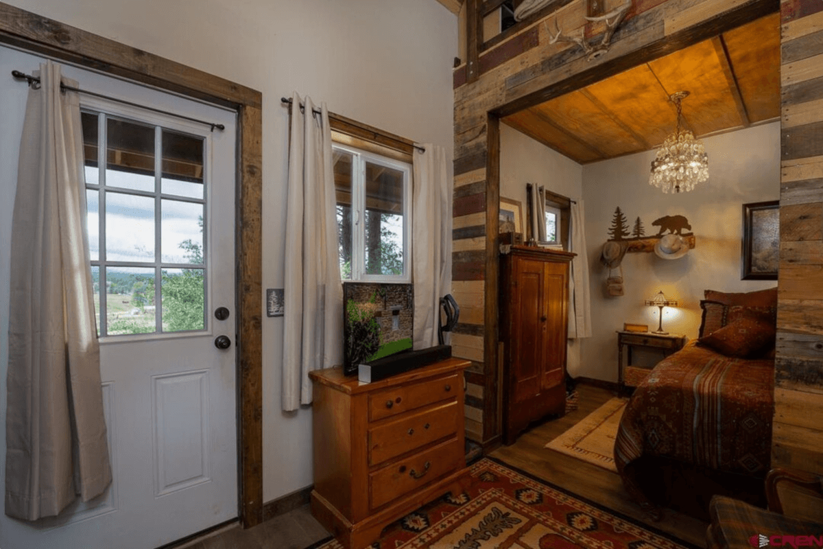 A luxurious chandelier hangs in the bedroom of this tiny log cabin.