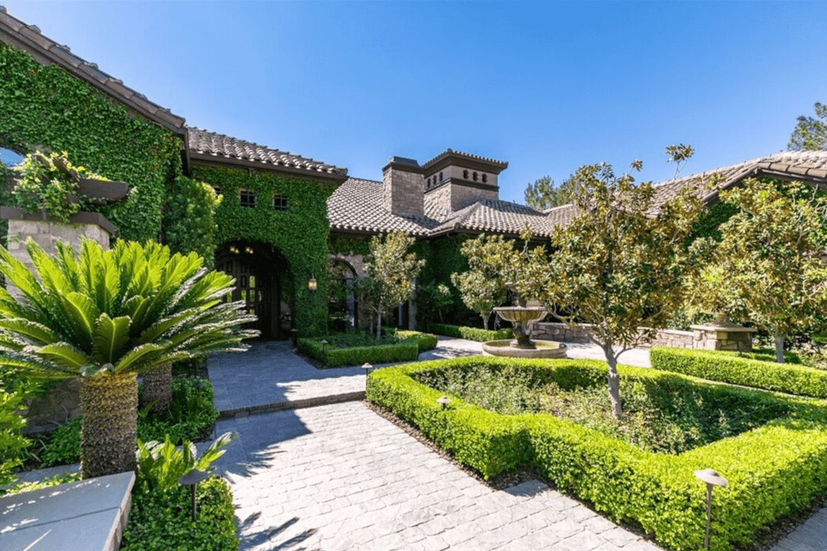 The outside of 47 Olympia Hills Circle is filled with greenery, with hedges, trees, and ivy.