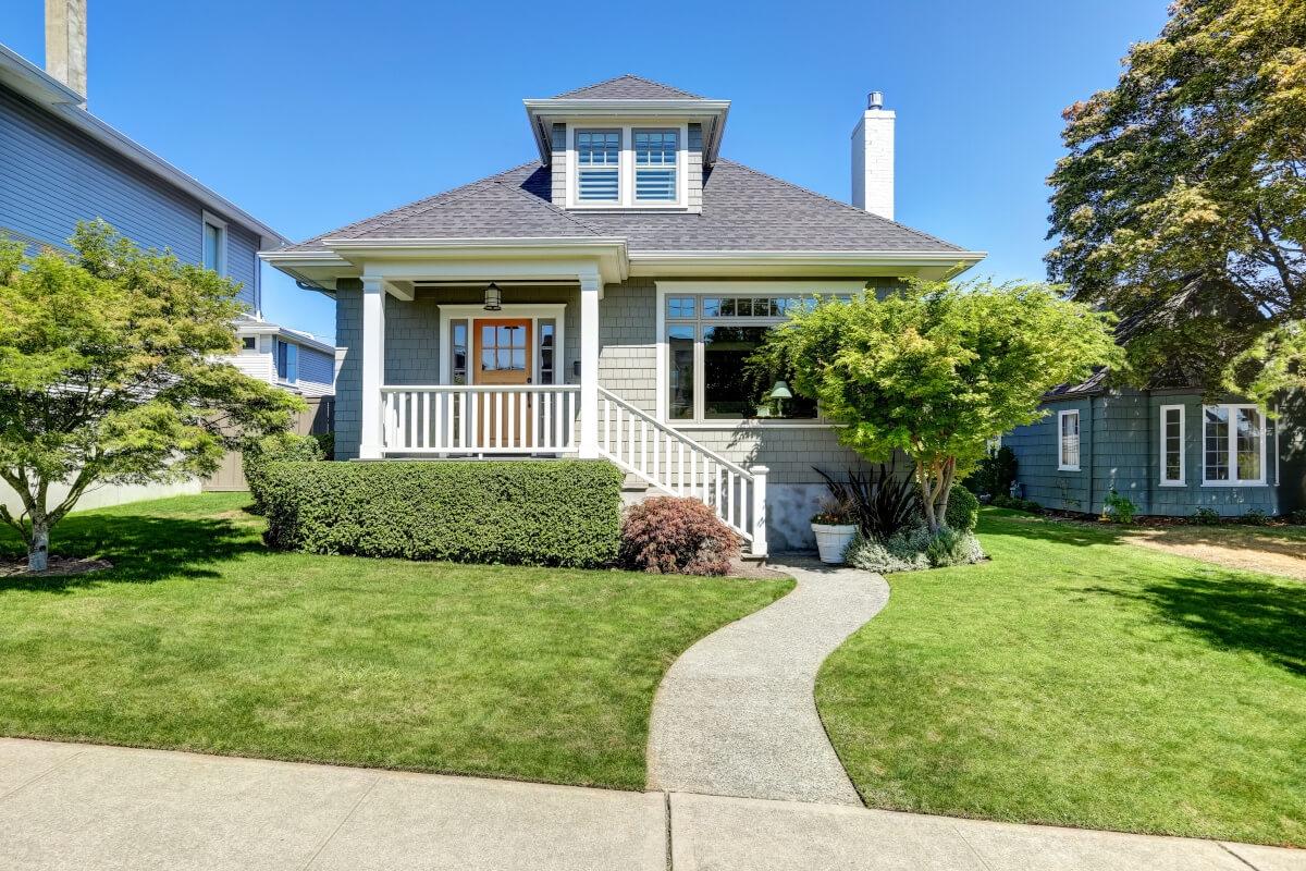 A Craftsman-style bungalow sits on a quiet suburban street.