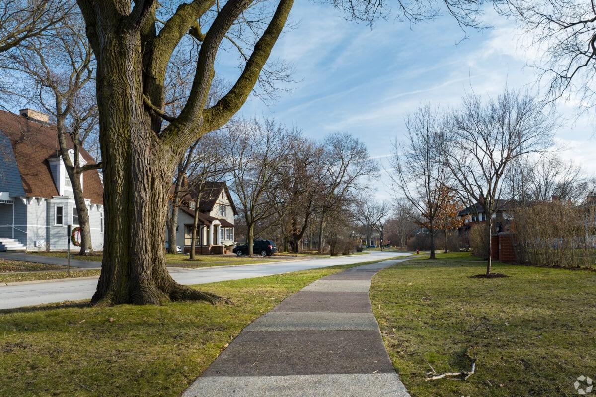 A residential street in Riverside, Illinois, shows well-kept sidewalks and front yards.