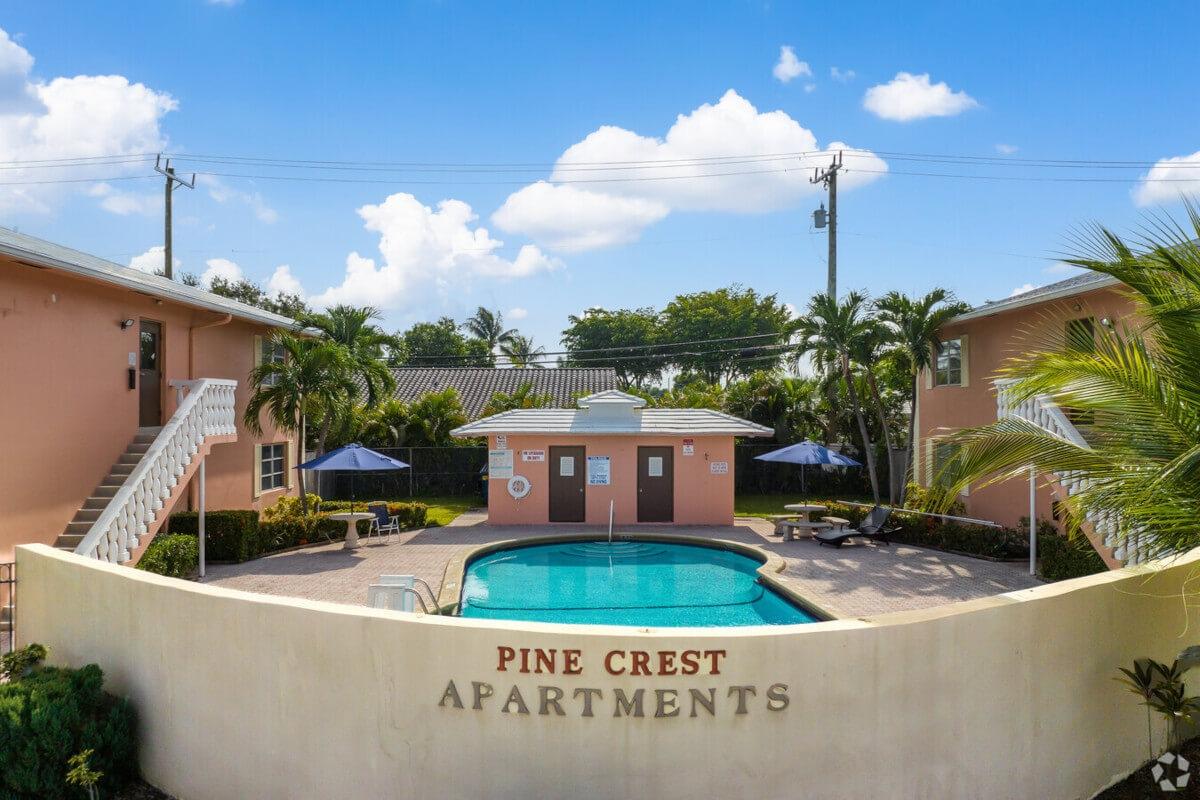 Pine Crest Apartments has a pool in the center of Spanish-style buildings.