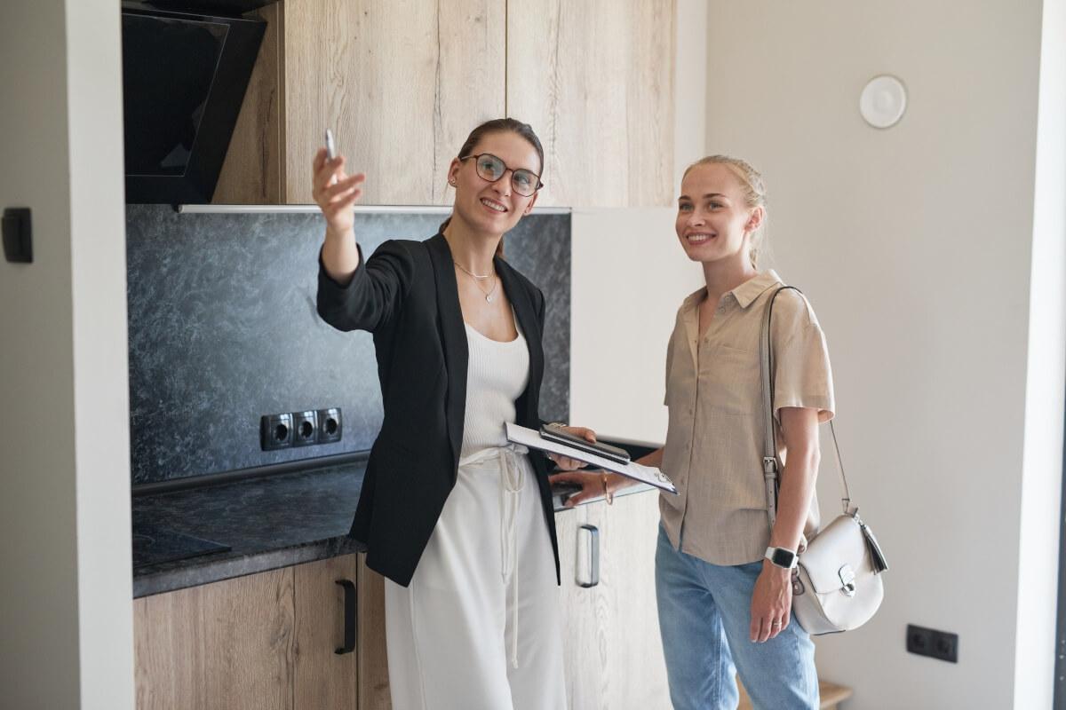 A property manager shows a young woman around an apartment unit.