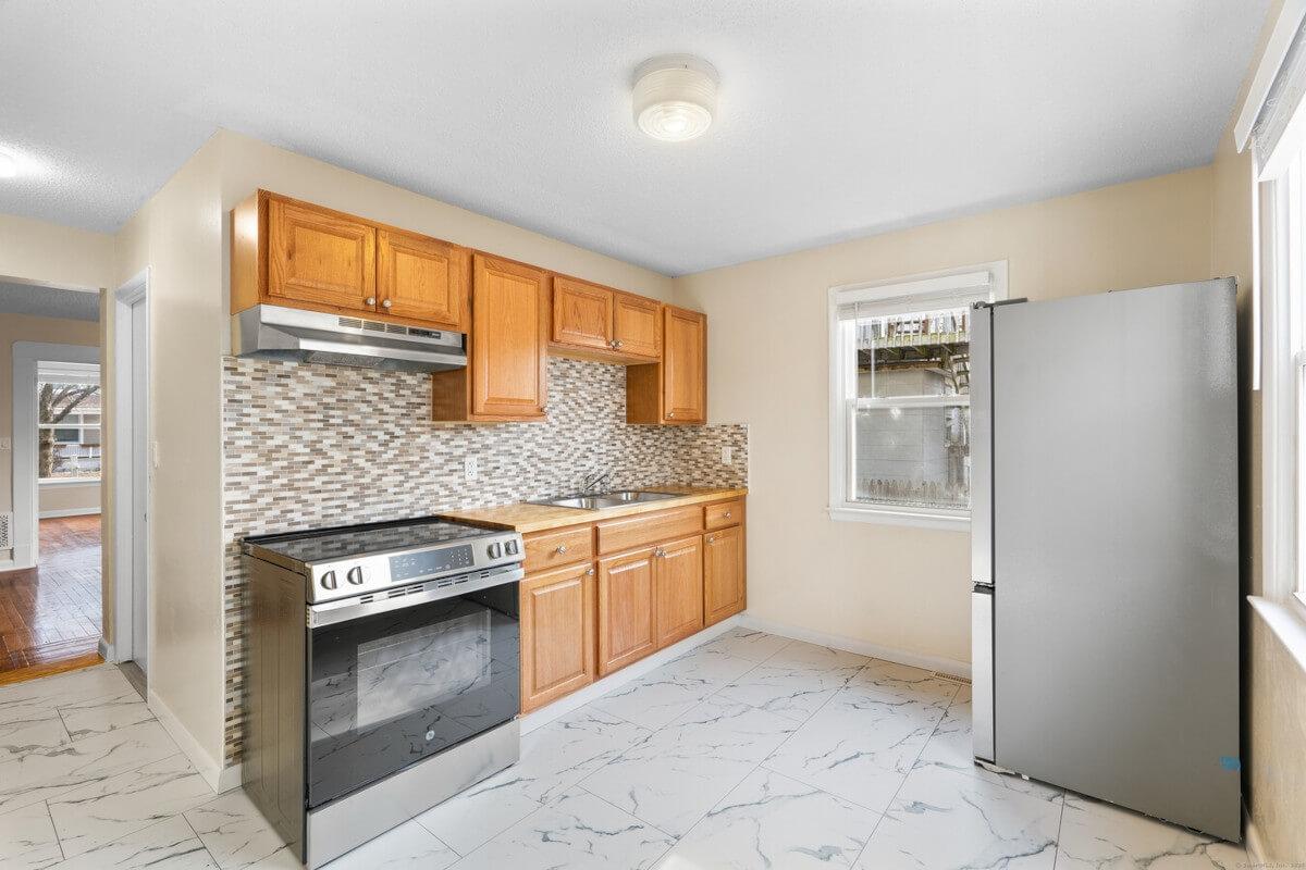 Tile flooring and modern backsplash are highlights of the kitchen in 1400 Ella T Grasso Blvd Unit B.