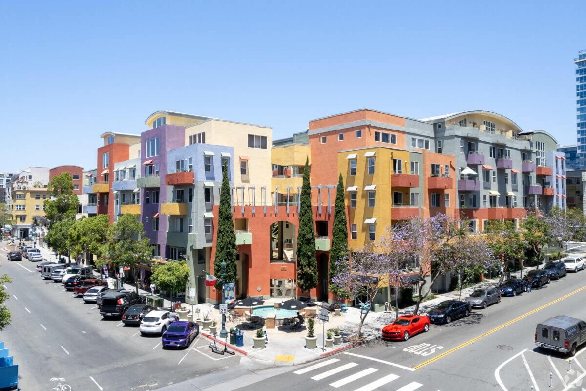 A multi-colored building with cars parked on the street.