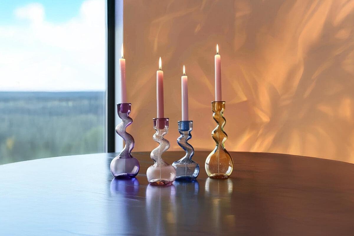 Four taper candles burn in abstract glass candle holders.