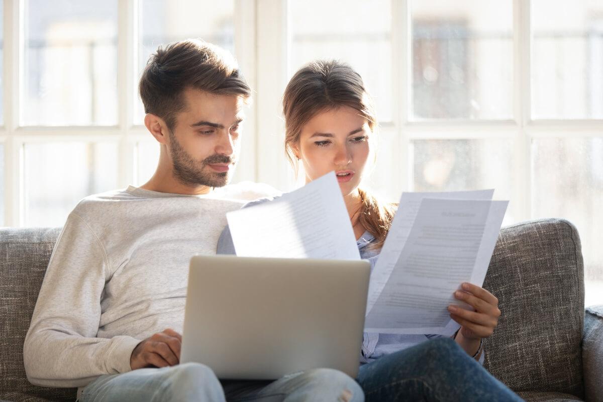 A young couple carefully reads the terms and conditions of a lease.