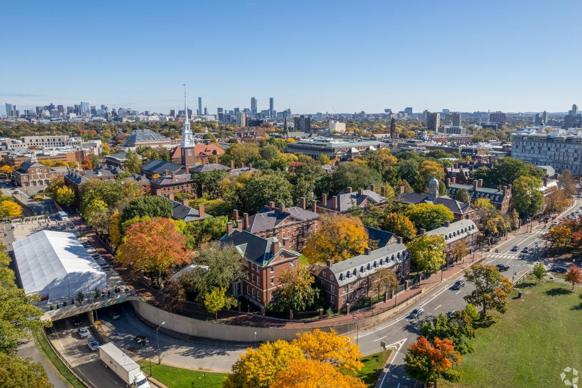 An aerial view of Harvard University shows the Boston skyline in the distance.