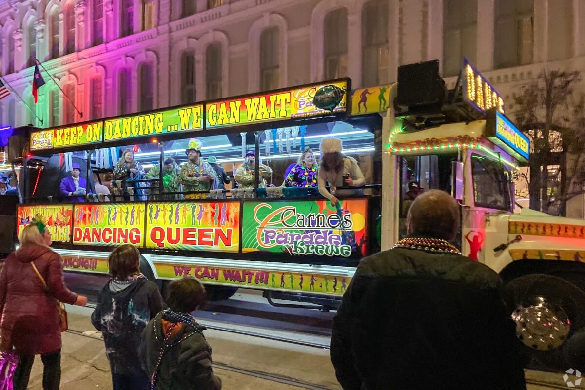 A lit-up party bus passes Mardi Gras revelers in Galveston, Texas.