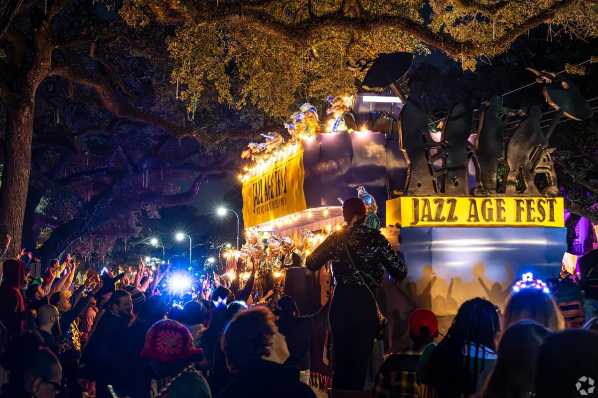 A Mardi Gras float with a sign that reads “Jazz Age Fest” rolls past a crowd in New Orleans.