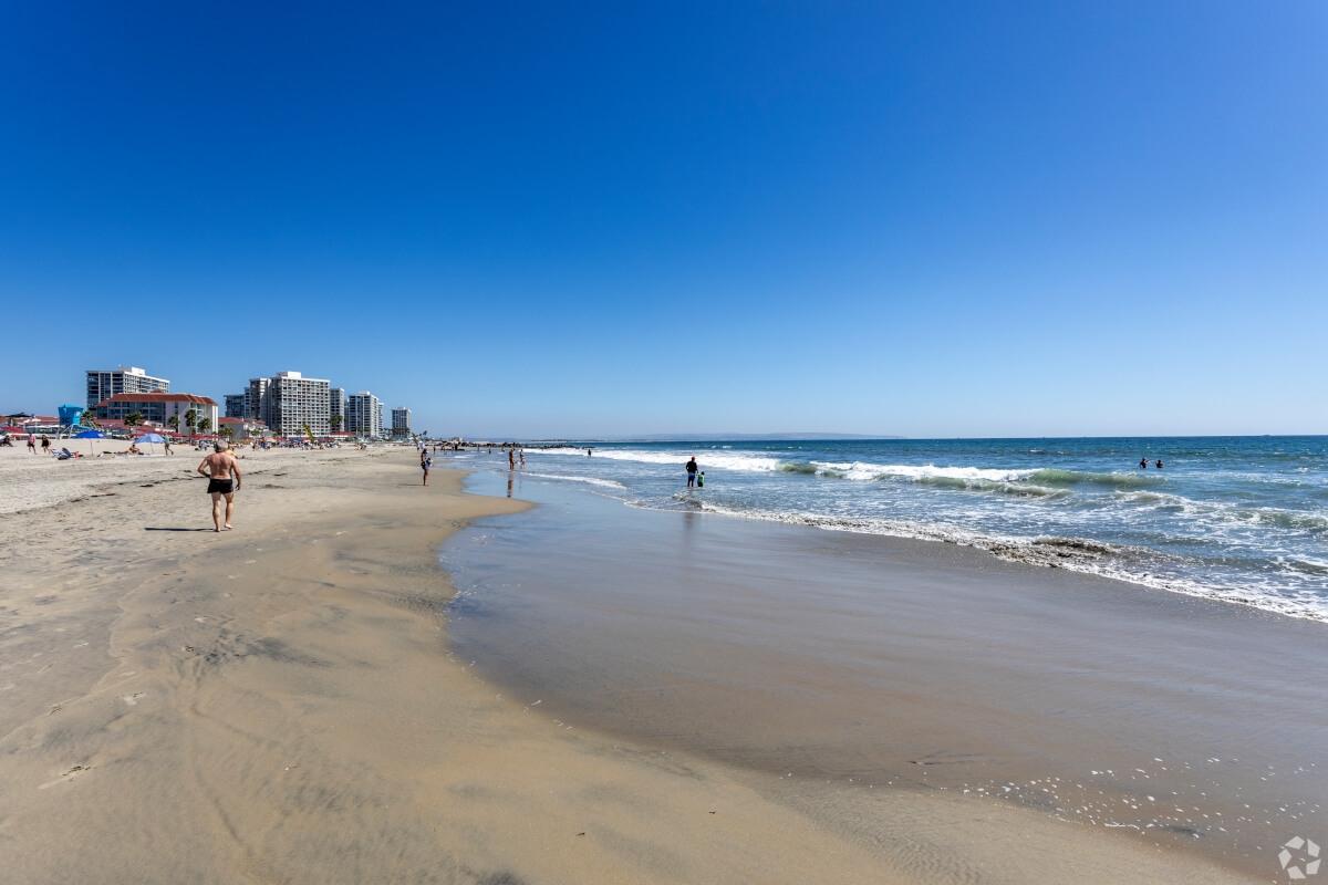 Beachgoers walk along the shoreline in Coronado.