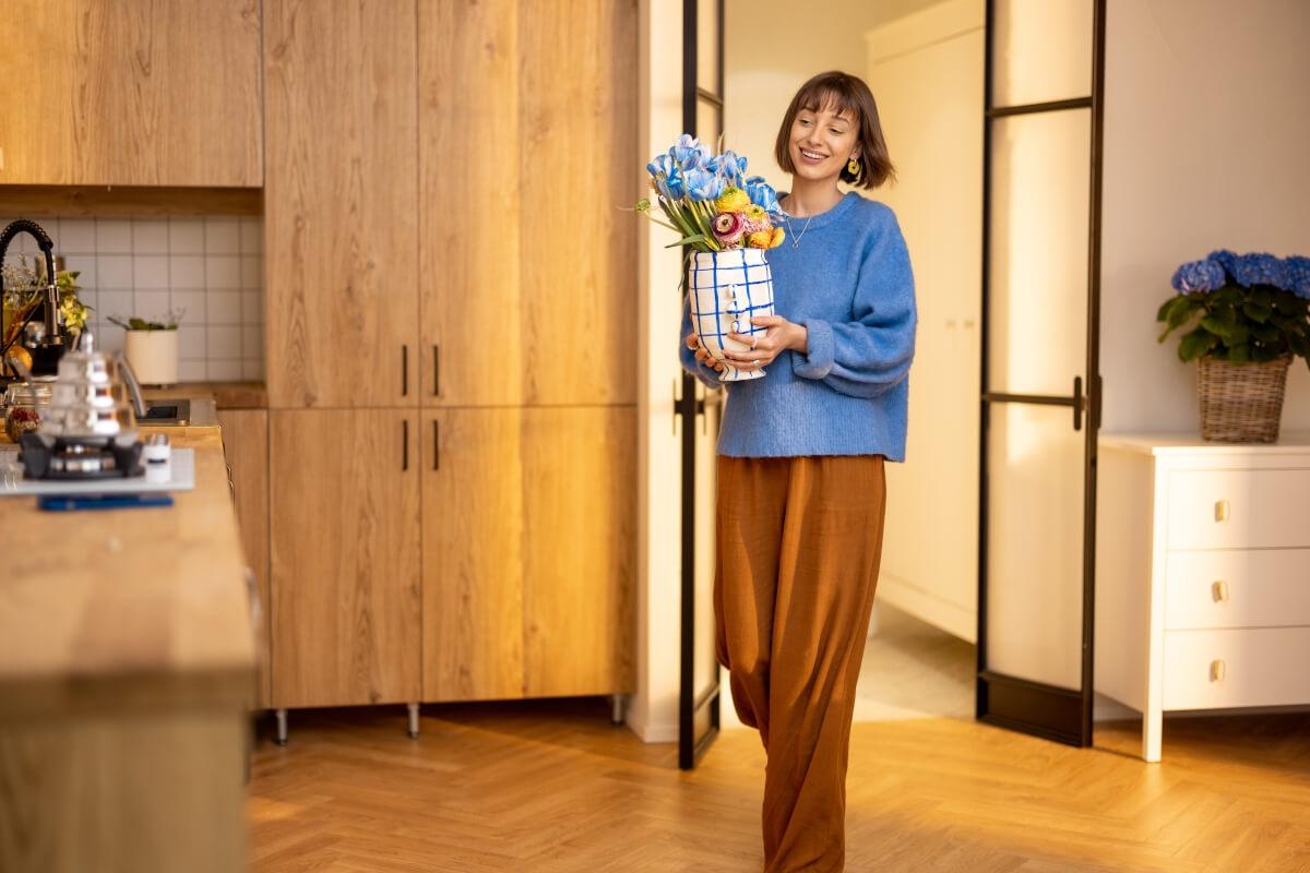 Lady walking with flowers in vase.