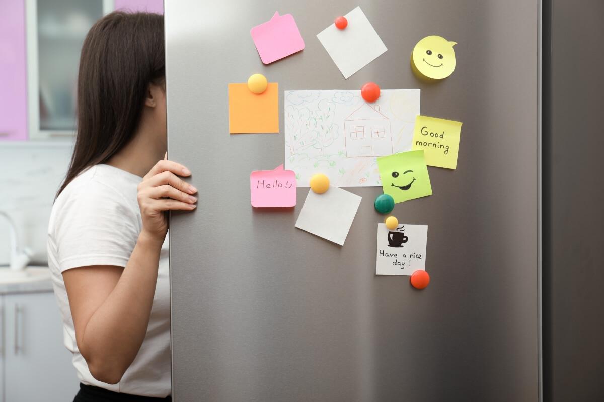 A bunch of magnets and stick notes on the door of an open fridge.