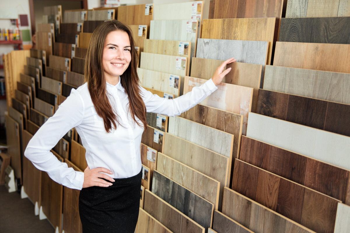 Smiling woman standing in front of many samples of flooring.