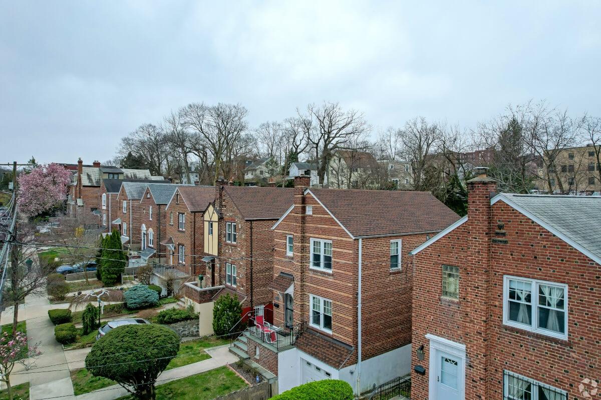 Red brick single-family homes with manicured front yards sit in a row in North Riverdale.