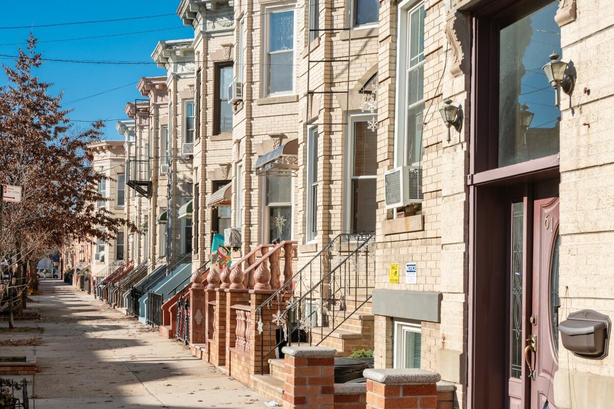 Greystone row homes along a sidewalk in the Ridgewood neighborhood of Queens.
