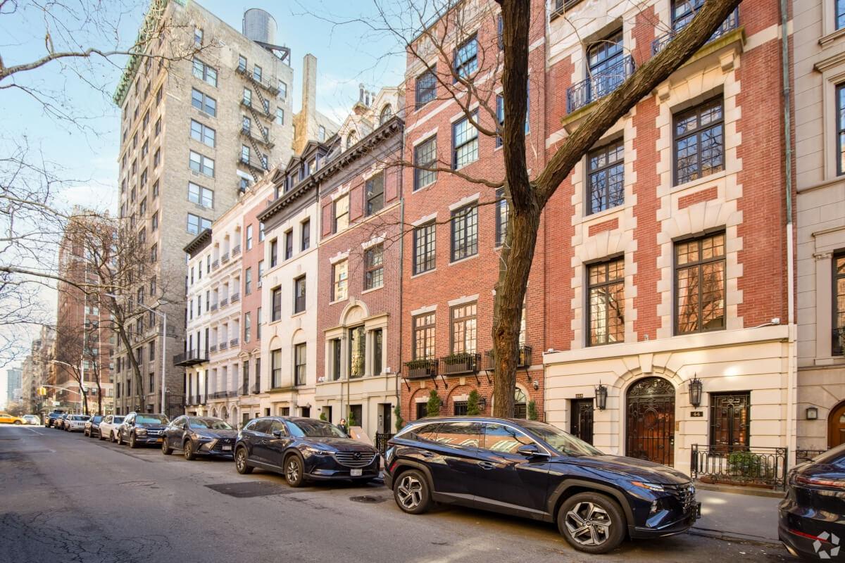 Cars parallel parked next to brownstones in the Upper East Side.