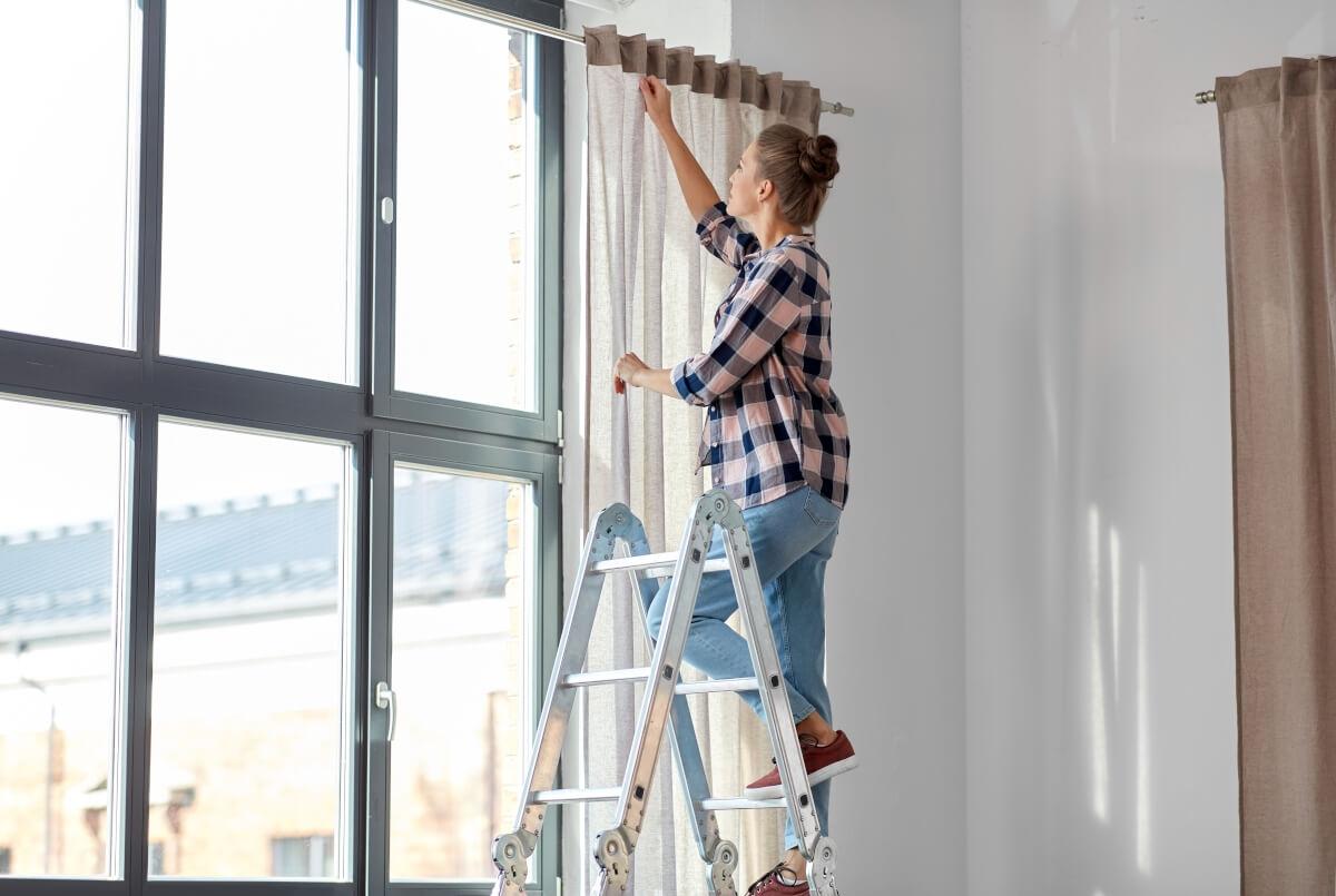 Renter hanging curtains in their home.