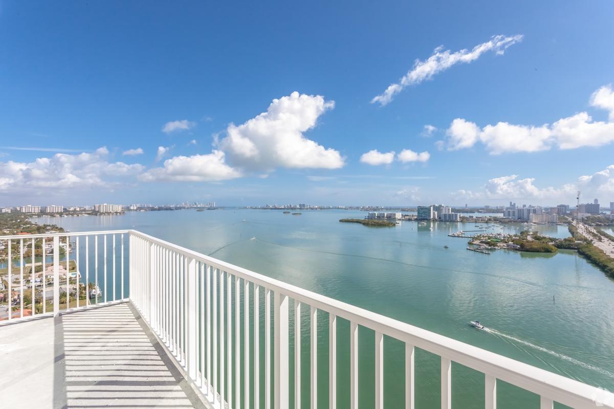 Panoramic balcony view of Biscayne Bay with clear blue skies and city skyline — desirable waterfront living near Miami apartments.