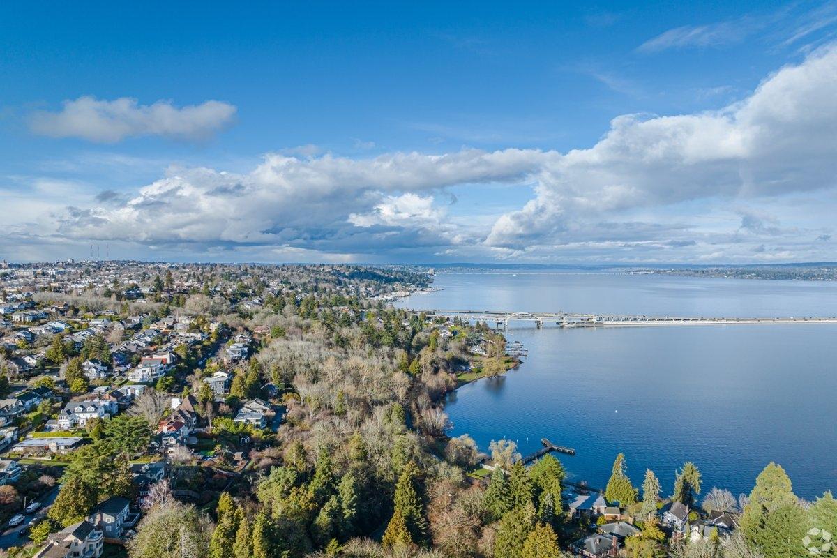 Drone photo of Mount Baker neighborhood in Seattle with tree-lined residential streets, Lake Washington shoreline, and I-90 floating bridge in view