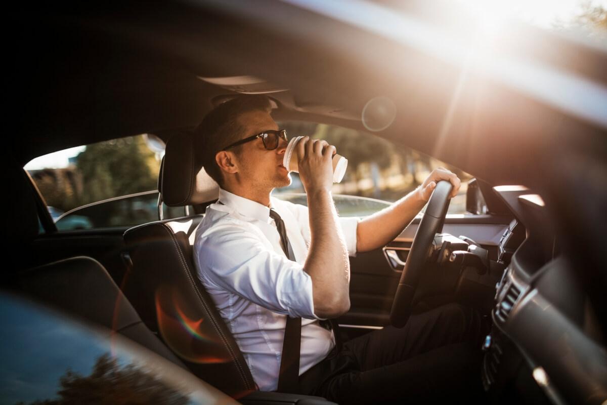 Man drinking his coffee as he drives to work.