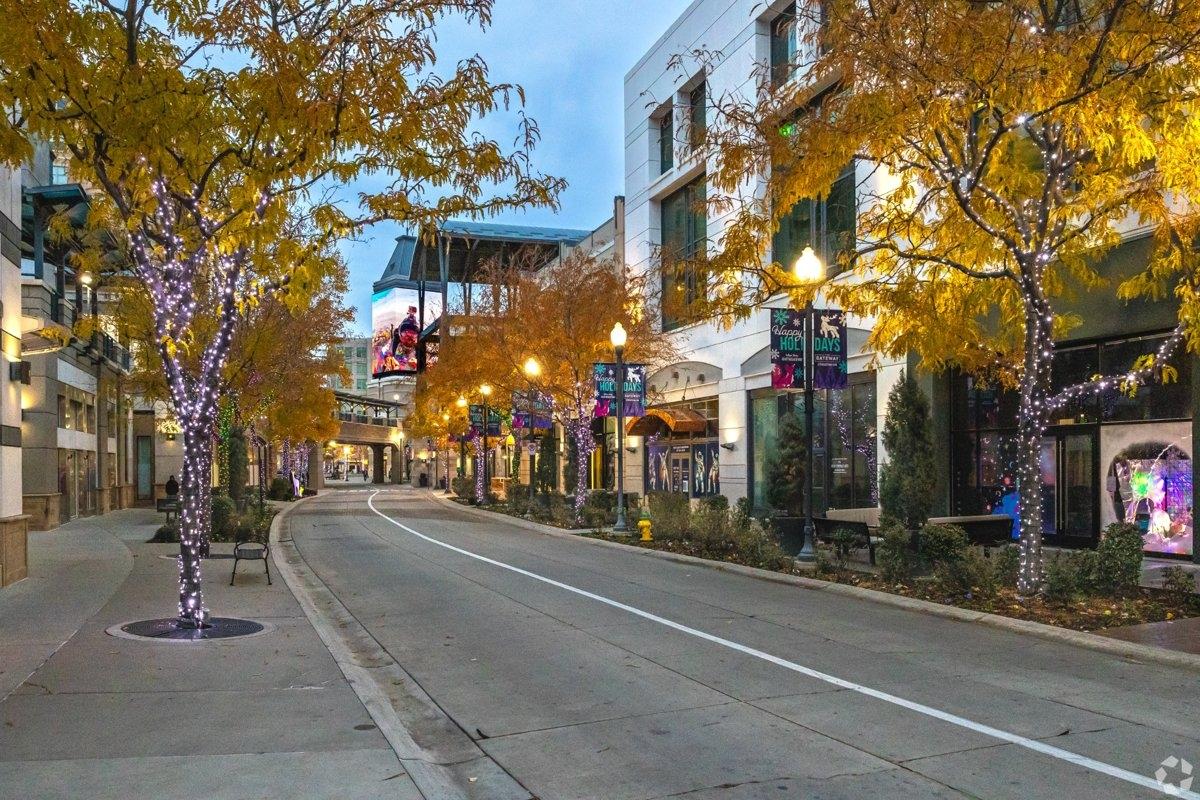 Holiday-lit street view of downtown Salt Lake City lined with shops and autumn-colored trees, ideal for urban apartment living.