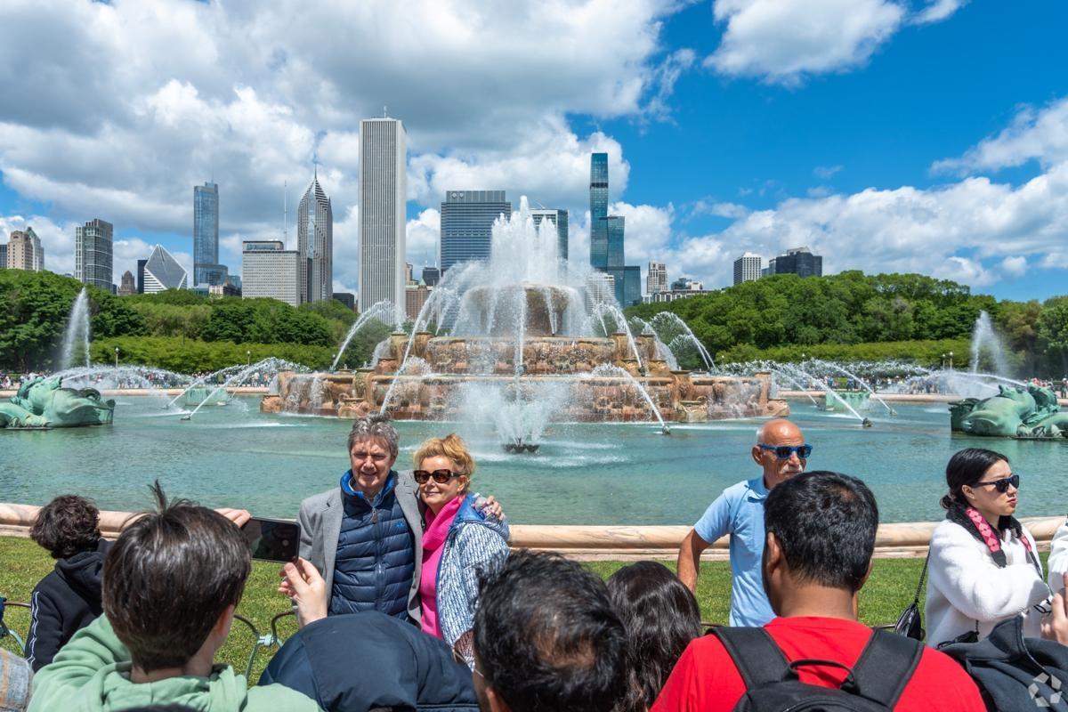 Tourists posing in front of Buckingham Fountain with the Chicago skyline in the background, a popular destination in Grant Park.