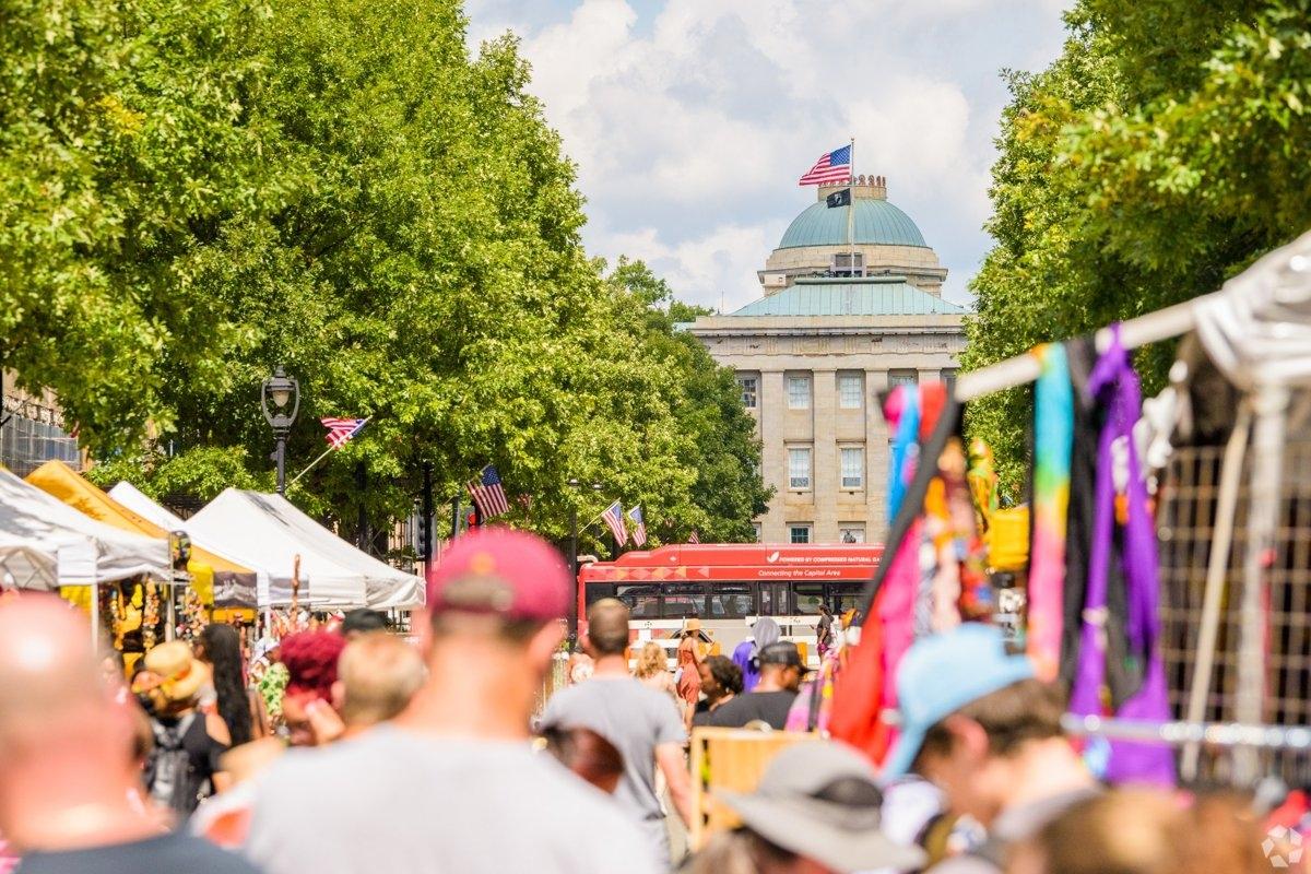 Street festival in downtown Raleigh NC with tents, vendors, and the North Carolina State Capitol building in the background.