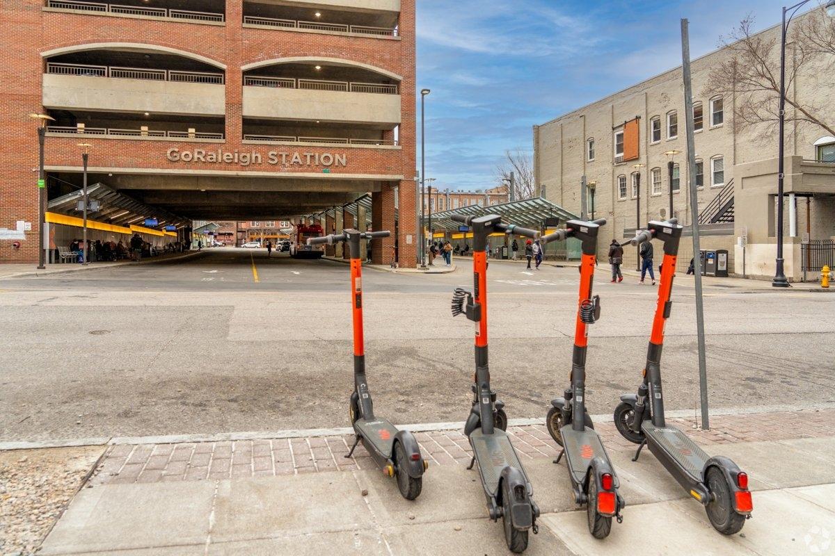 Electric scooters parked near GoRaleigh Station bus terminal in downtown Raleigh NC on a clear day.