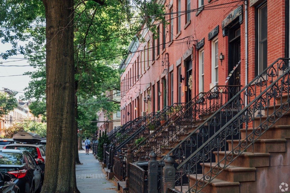 Tree-lined residential street in Hoboken featuring classic red-brick row houses and stoops – family-friendly streetscape in Western Edge.